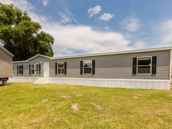 Gray manufactured home with black shutters and white trailer skirt