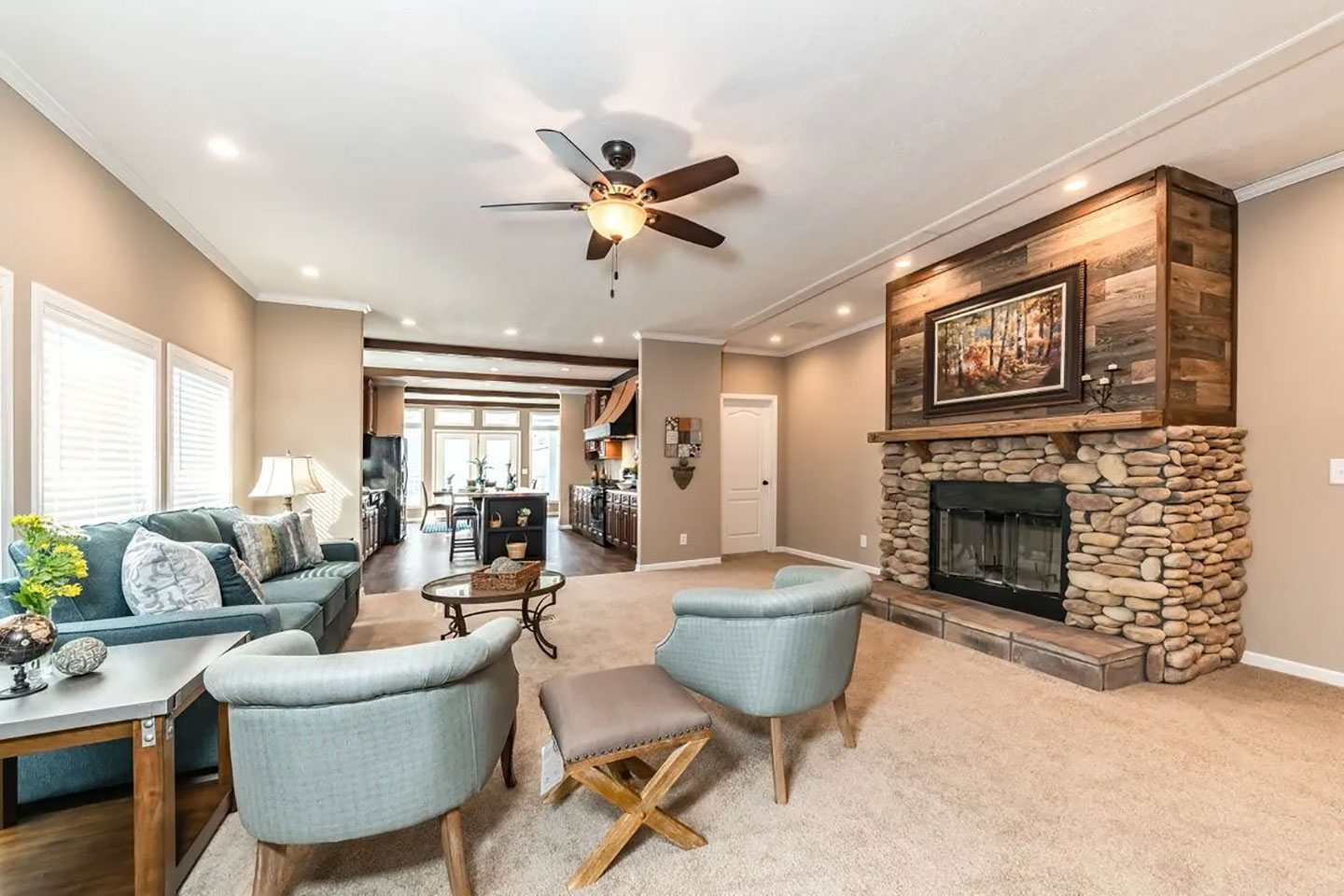A living room with a stone fireplace and ceiling fan.