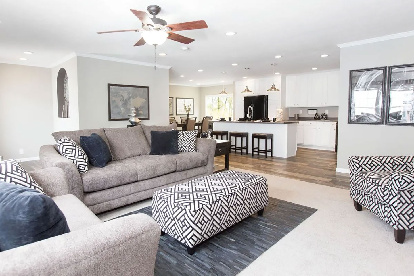 A living room with gray furniture and a ceiling fan.