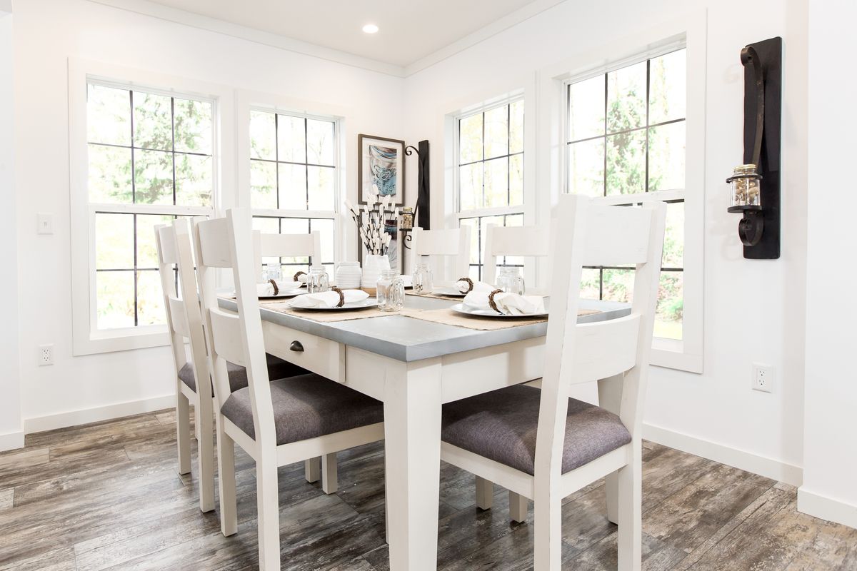 A dining room with a white table and chairs.