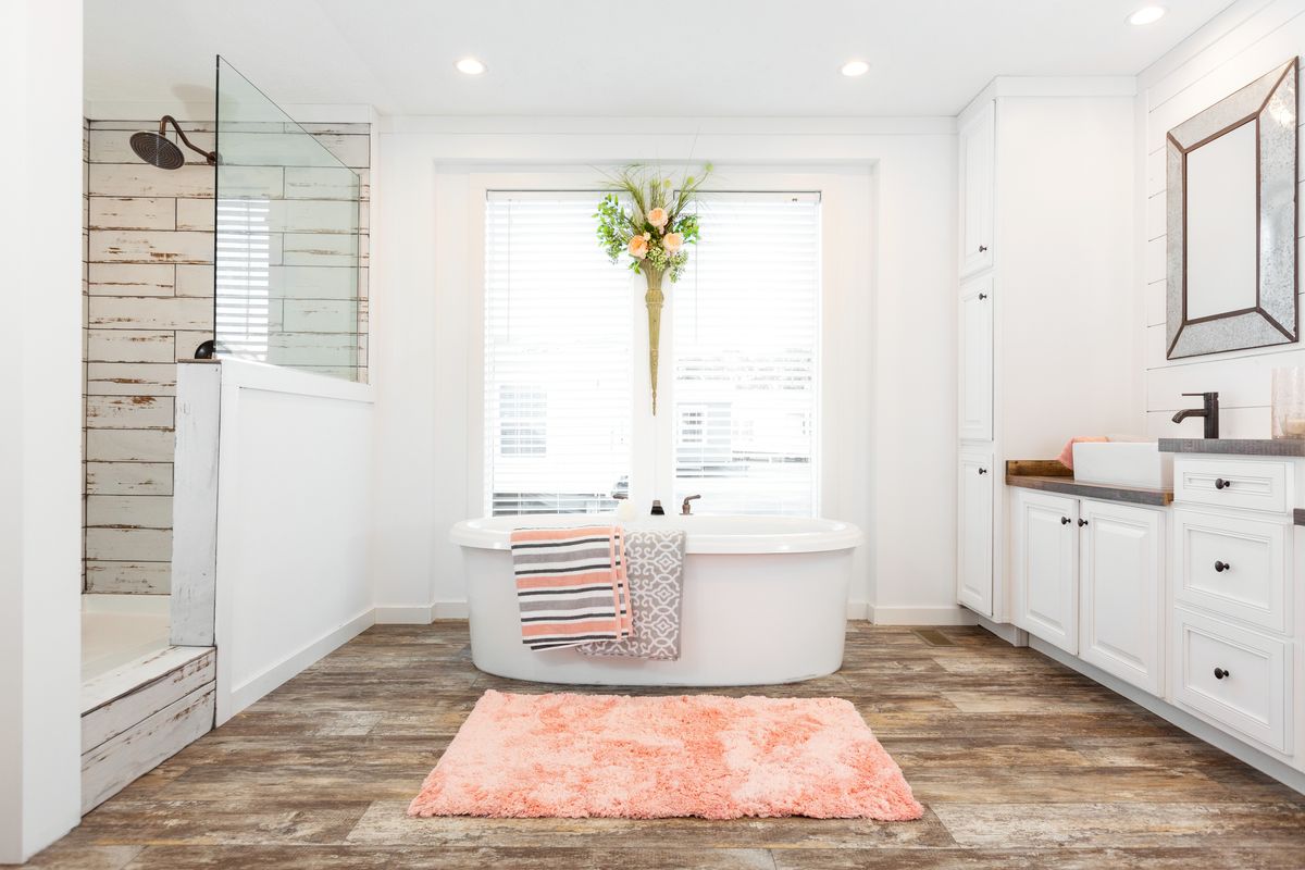 A white bathroom with a bathtub and a rug.
