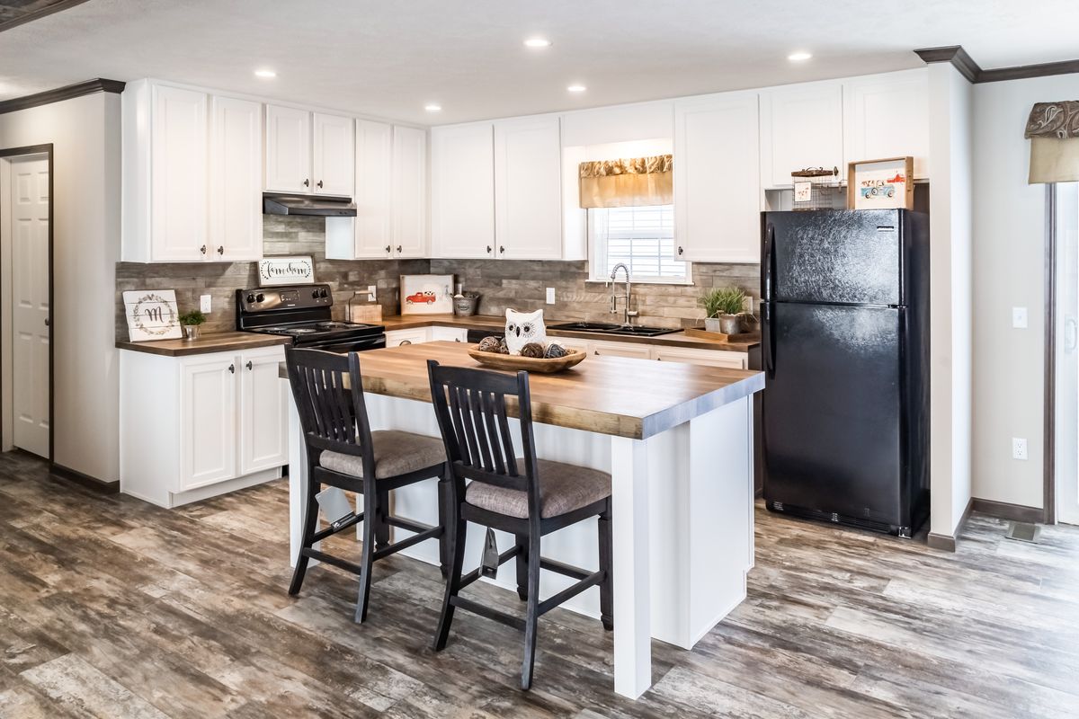 A kitchen in a mobile home with hardwood floors.