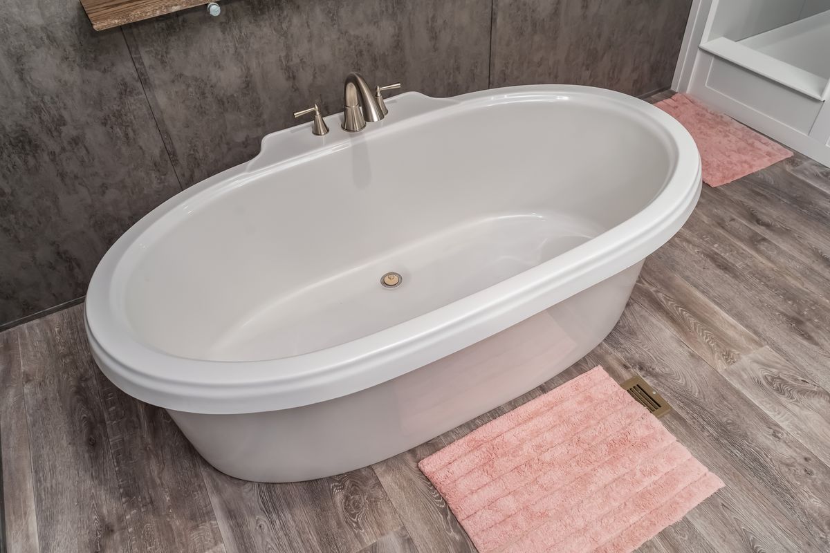 0a5f897d-d3ac-4f3c-8bdf-746d5f962d2b A white bathtub with a pink rug on the floor.