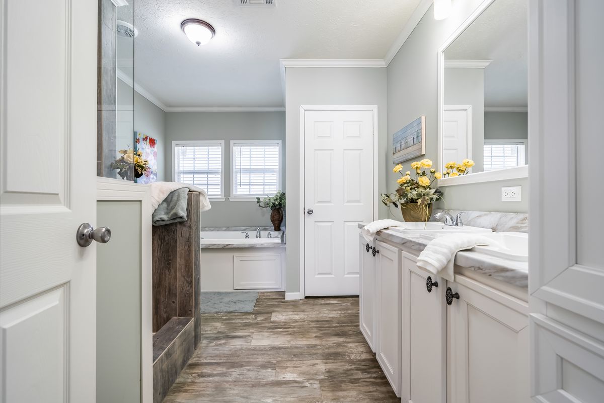 0afe0770-528e-48a4-8dea-fc9b60c7e357 A bathroom with white cabinets and wood floors.