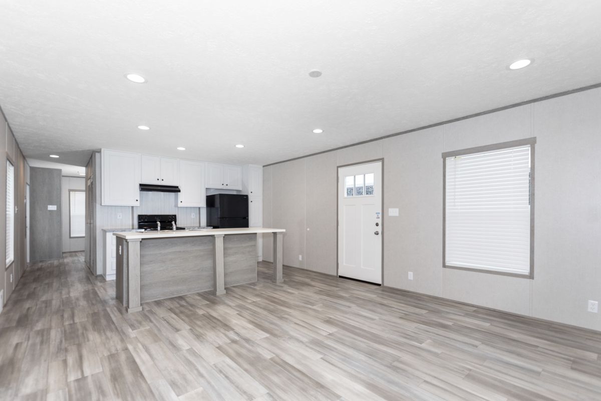 0c49fcbb-c155-4d3d-ae57-b8181638b8f8 An empty kitchen with wood floors and white walls.