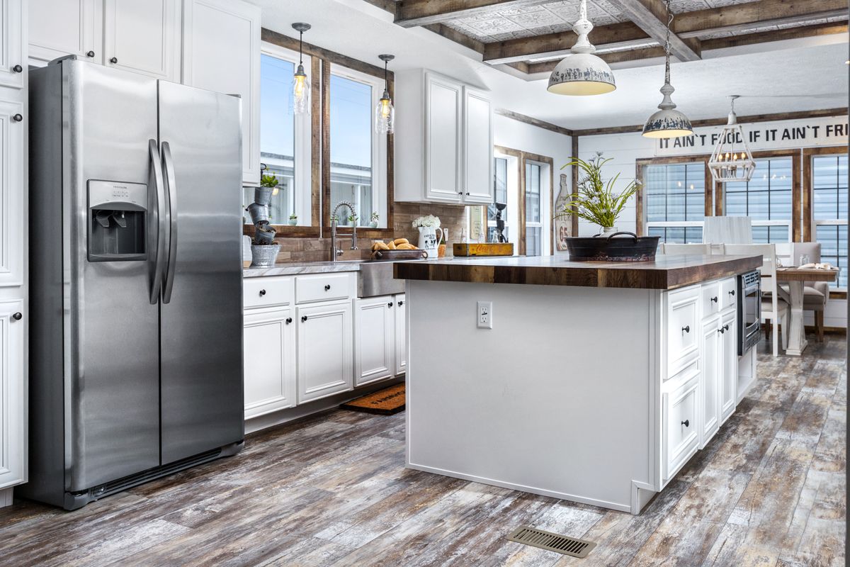 A white kitchen with wood floors and wooden beams.