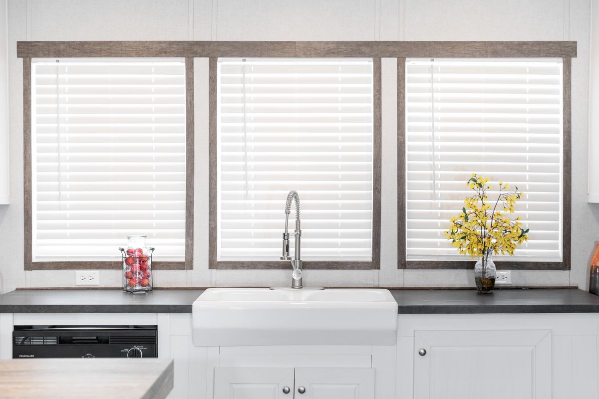 A kitchen with white cabinets and white blinds.