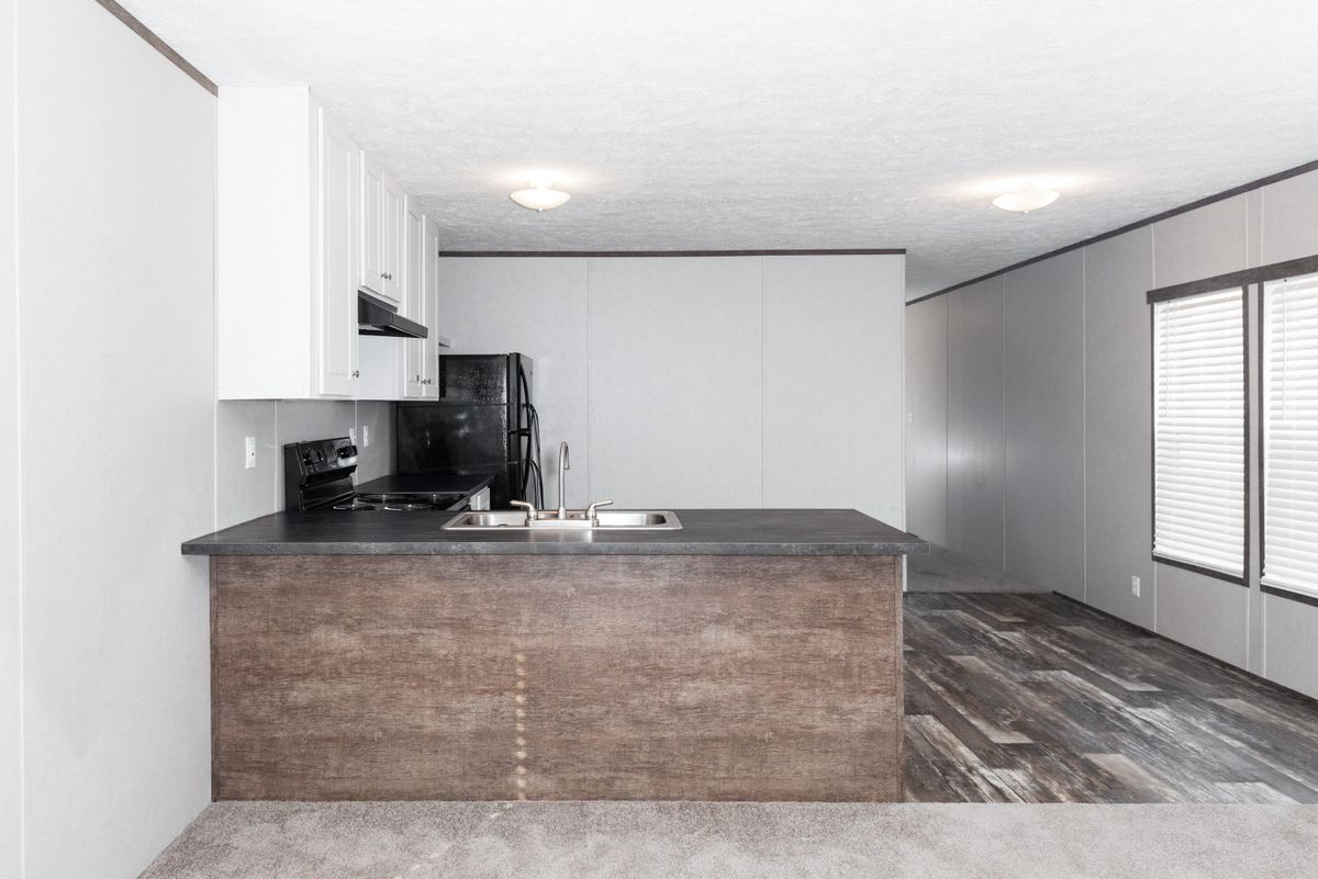 11a8eb77-3546-441e-a471-81fc8f526d17 A kitchen in a mobile home with hardwood floors.
