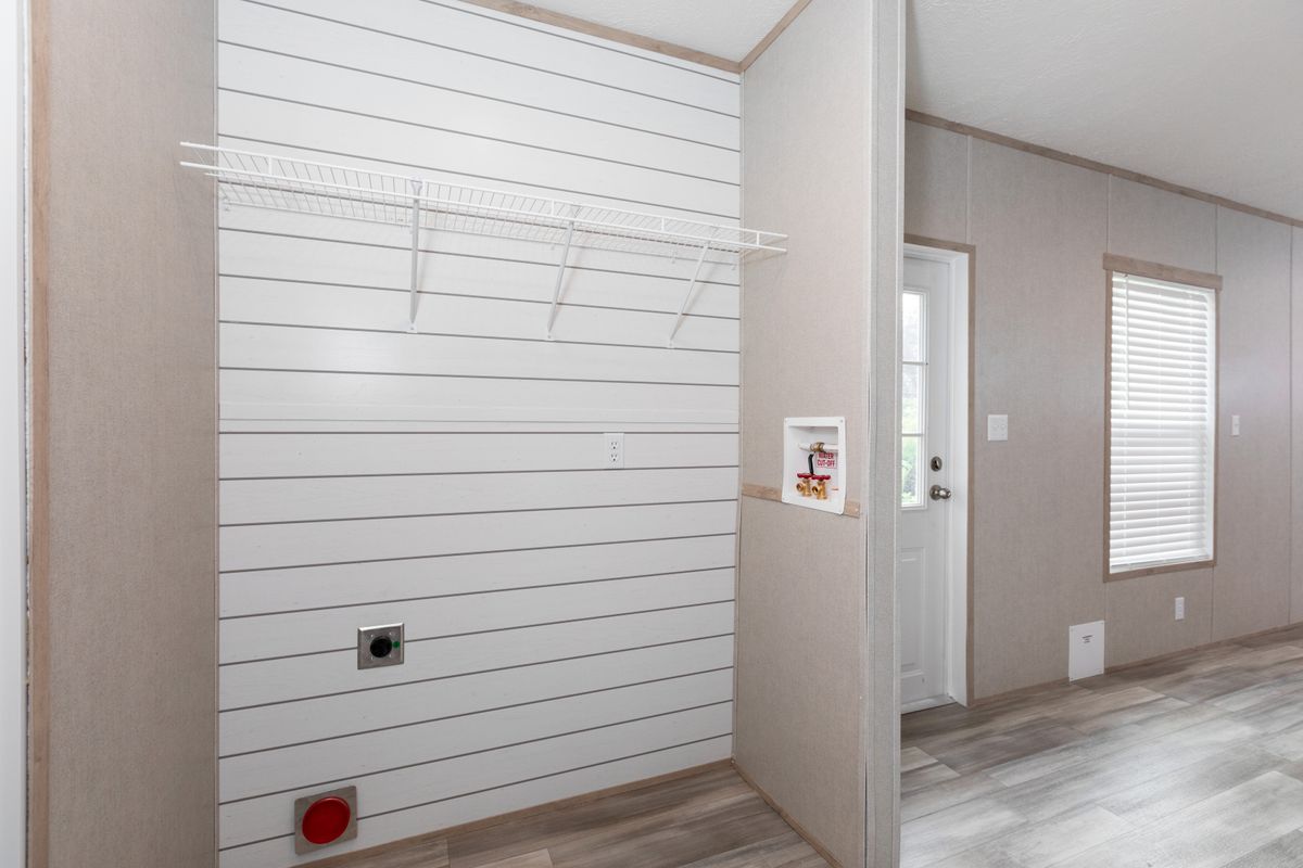 13122690-505f-4ea0-aa9a-c4c2319e406e A room in a mobile home with white walls and wood floors.