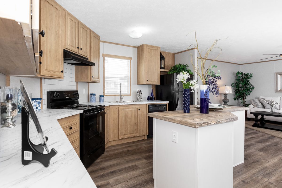 159fdc7d-5630-4681-9efd-b58c39f794b4 A kitchen in a mobile home with hardwood floors.
