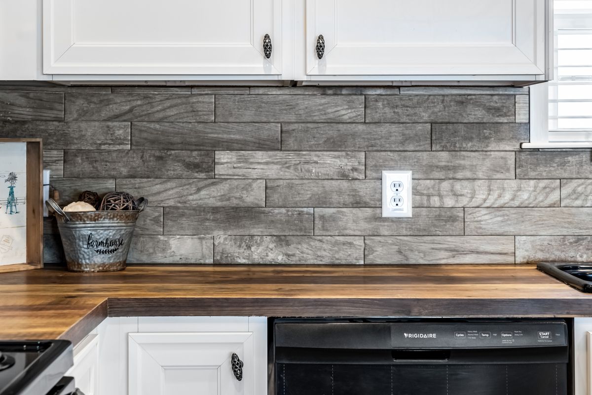 A kitchen with a wooden counter top and tile backsplash.
