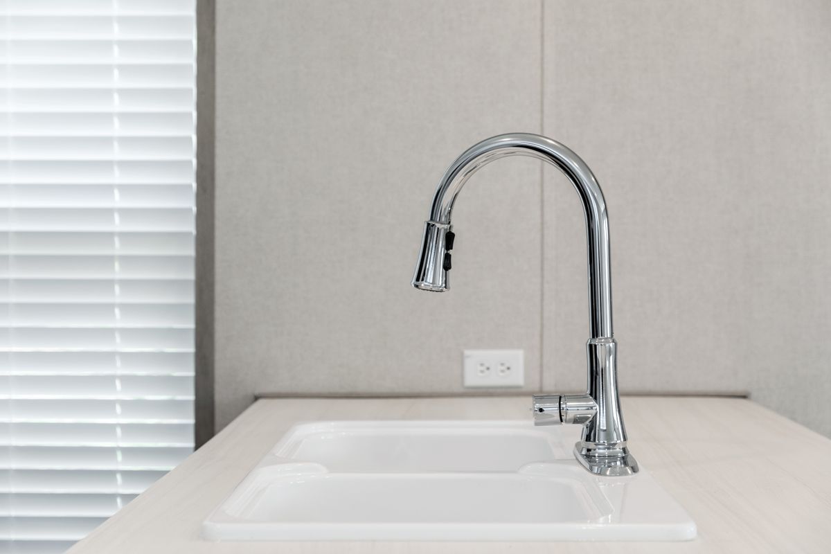 17a226d8-c066-4747-bccb-c7eff777942d A white kitchen sink with a chrome faucet.