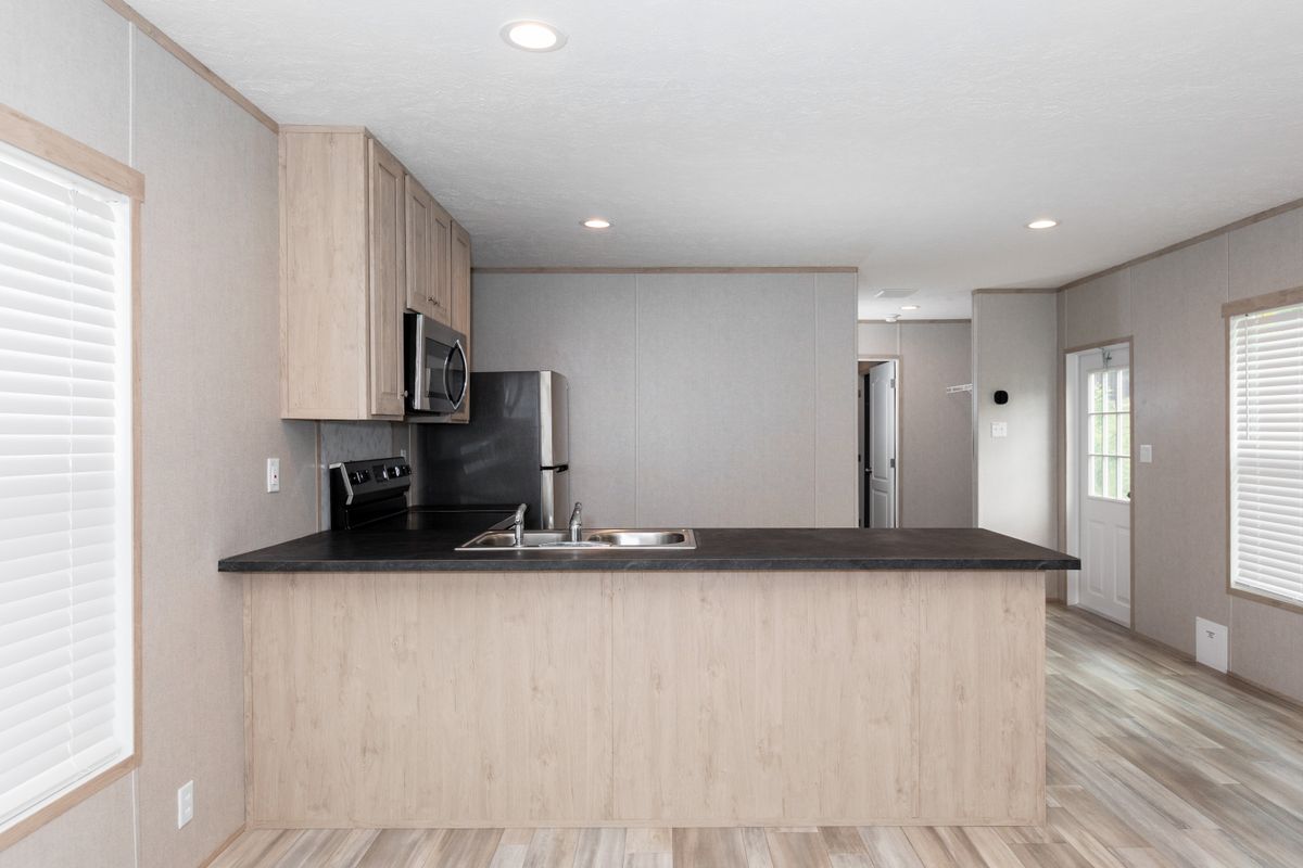 1e7bc874-6e11-40f1-b3e1-c39ce7f224f9 A kitchen in a mobile home with wood floors.