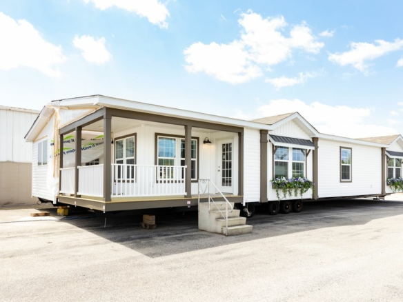 A white mobile home on a trailer in a parking lot.