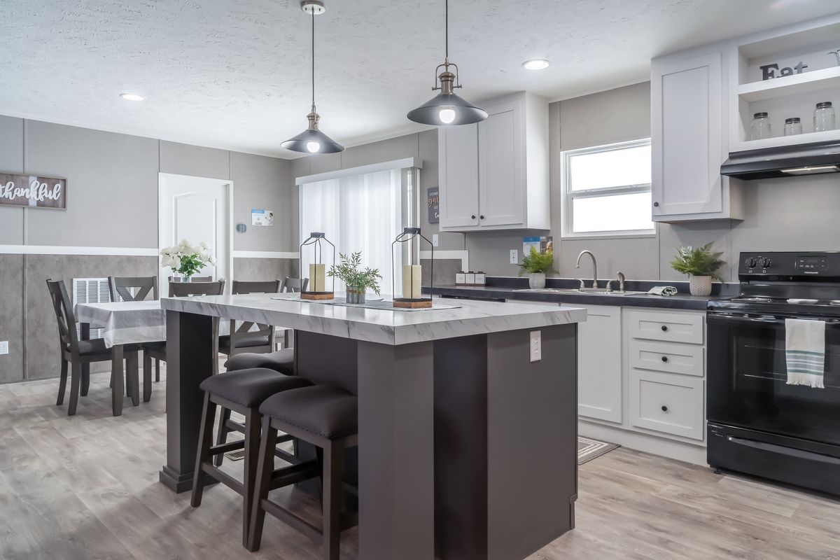 A kitchen with white cabinets and black counter tops.