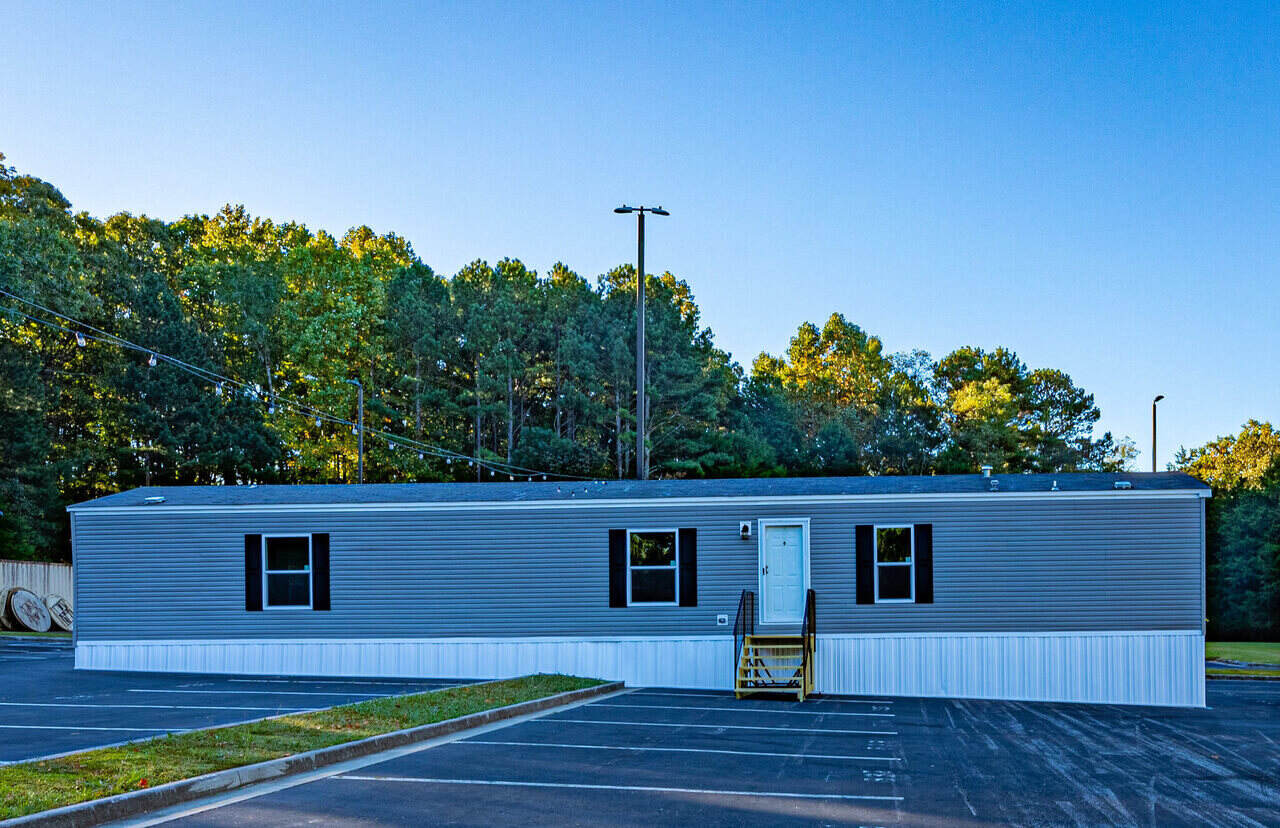 A gray mobile home sitting in a parking lot.