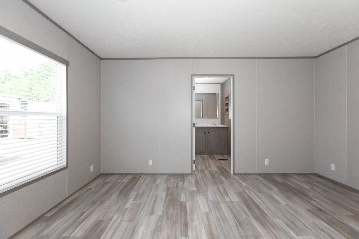 2317f708-d0dd-427a-9660-8a29da109561 An empty room with wood floors and a window.