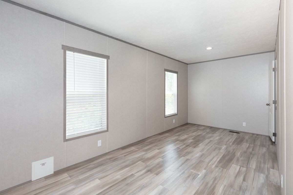 283c9489-ebb4-4d2a-9f0c-960e13b5d5a7 An empty room with hardwood floors and windows.