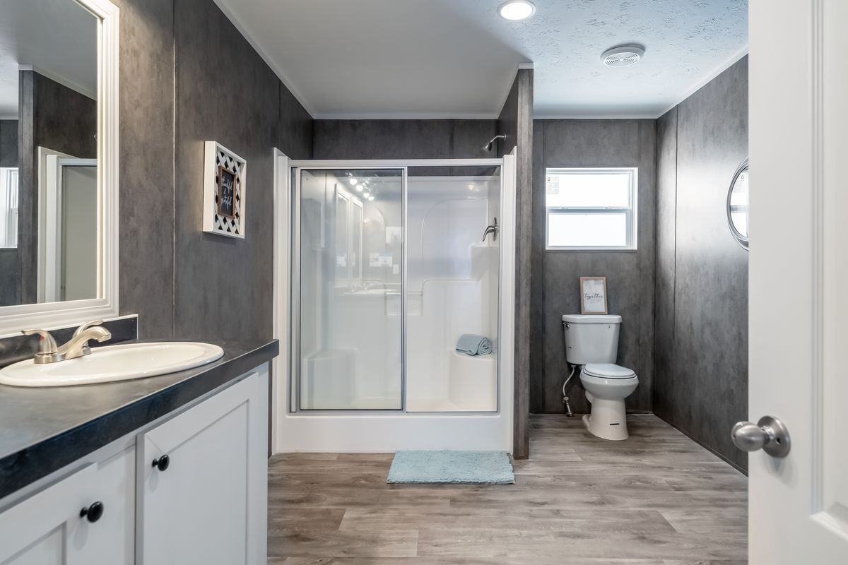 A bathroom with gray walls and wood floors.