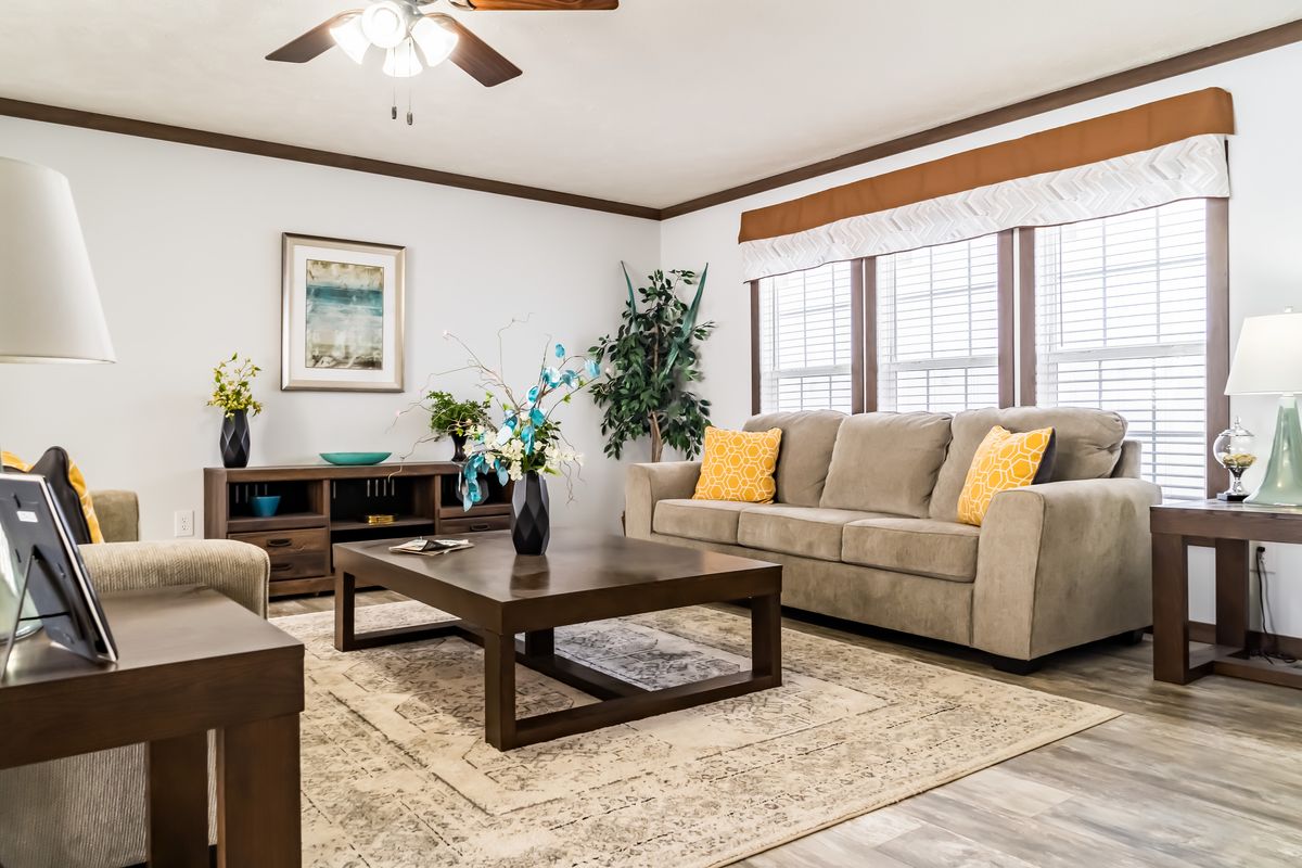 A living room with brown furniture and a ceiling fan.