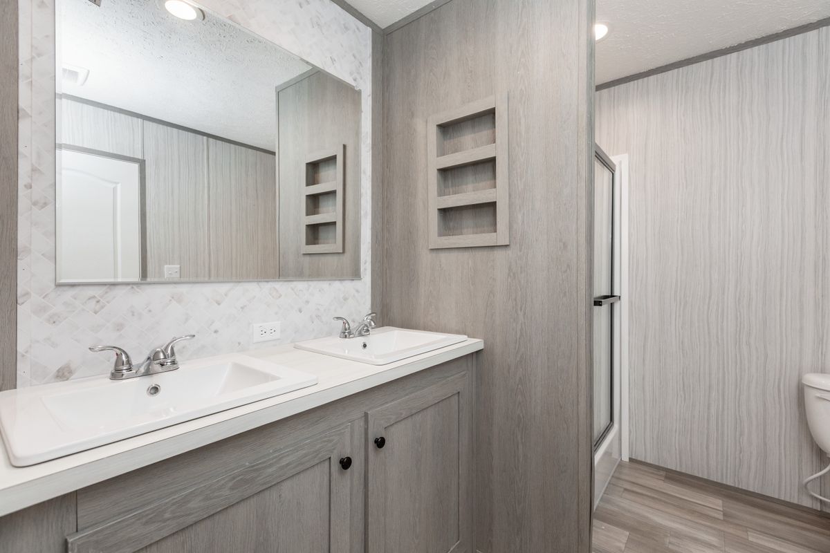 2b89687e-ab4b-4d7d-a501-df507ba7aa7b A bathroom with a sink, toilet and mirror.
