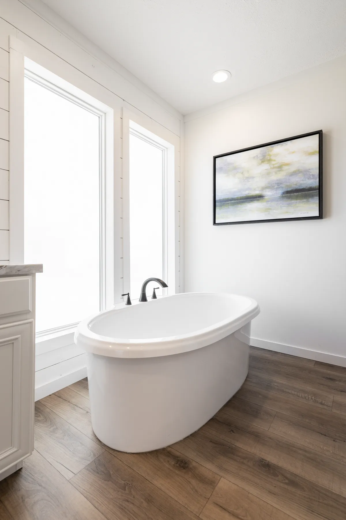 30cc4a3f-8f69-47e0-87ae-14af93aea6d1 A white bathroom with wooden floors and a bathtub.