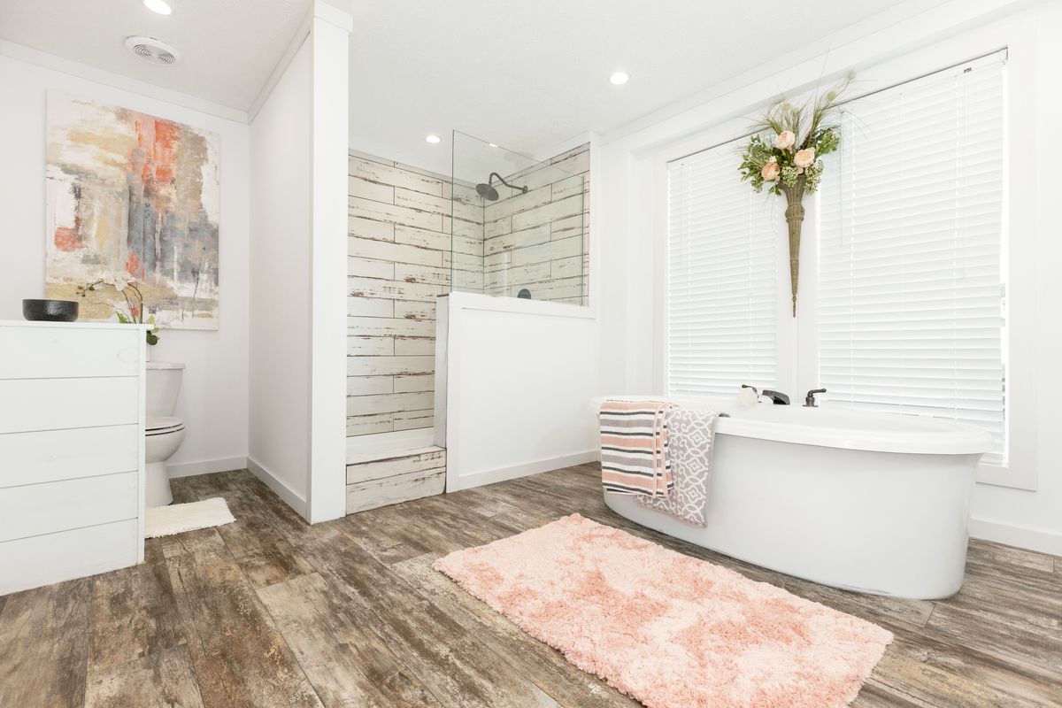 A white bathroom with wood floors and a tub.