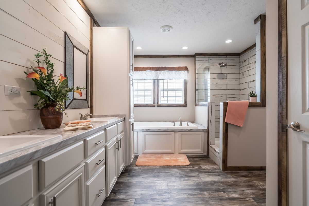 A bathroom with white cabinets and wood floors.