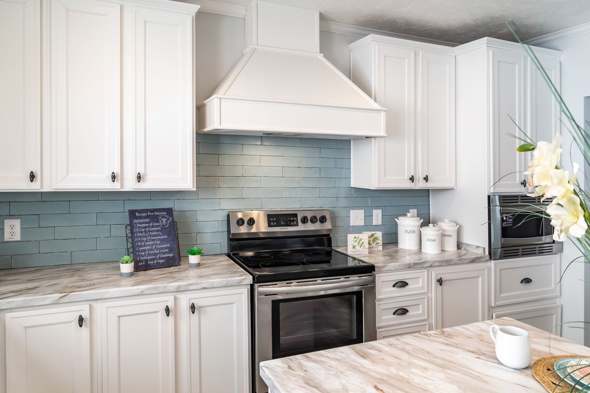 36b98607-040c-44ef-b3f6-c0ad248dc56d A kitchen with white cabinets and blue tile.