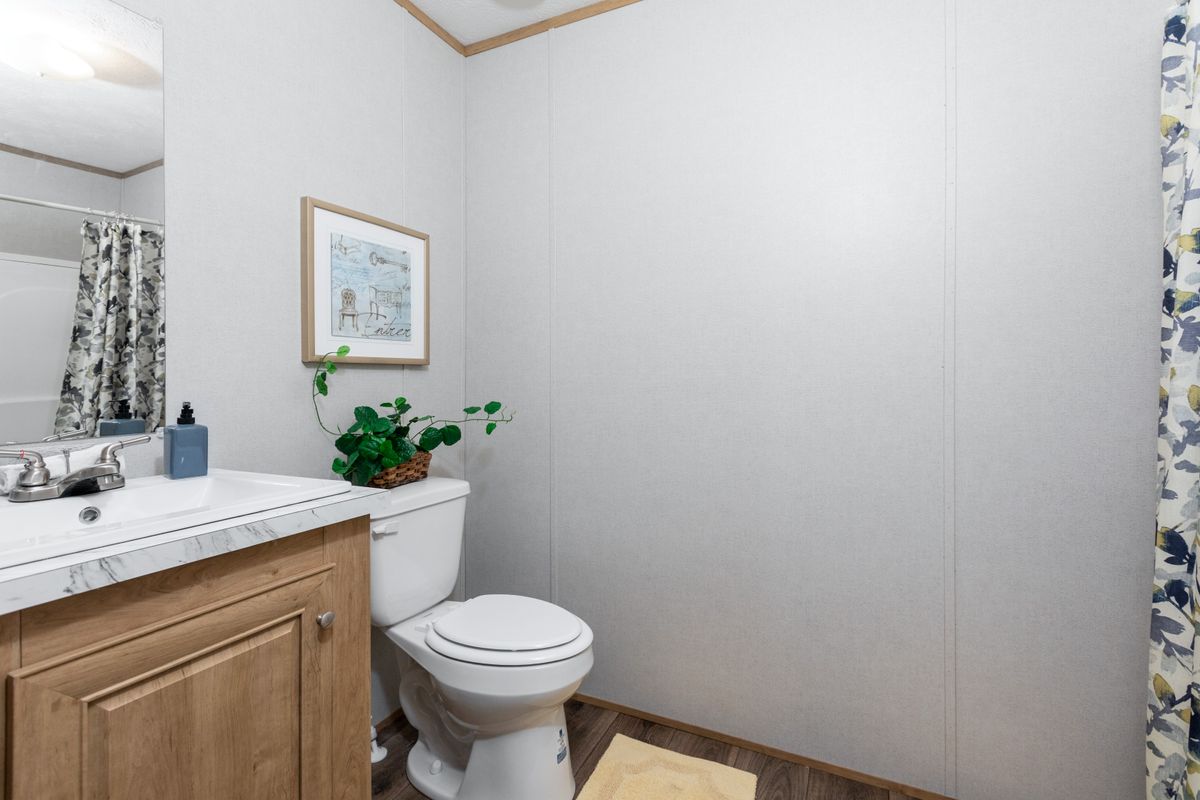 A bathroom in a mobile home with a toilet and shower.