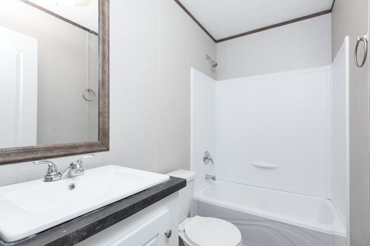 39c48279-eca4-4672-b583-83339bd66e07 A bathroom with a toilet, sink and mirror.