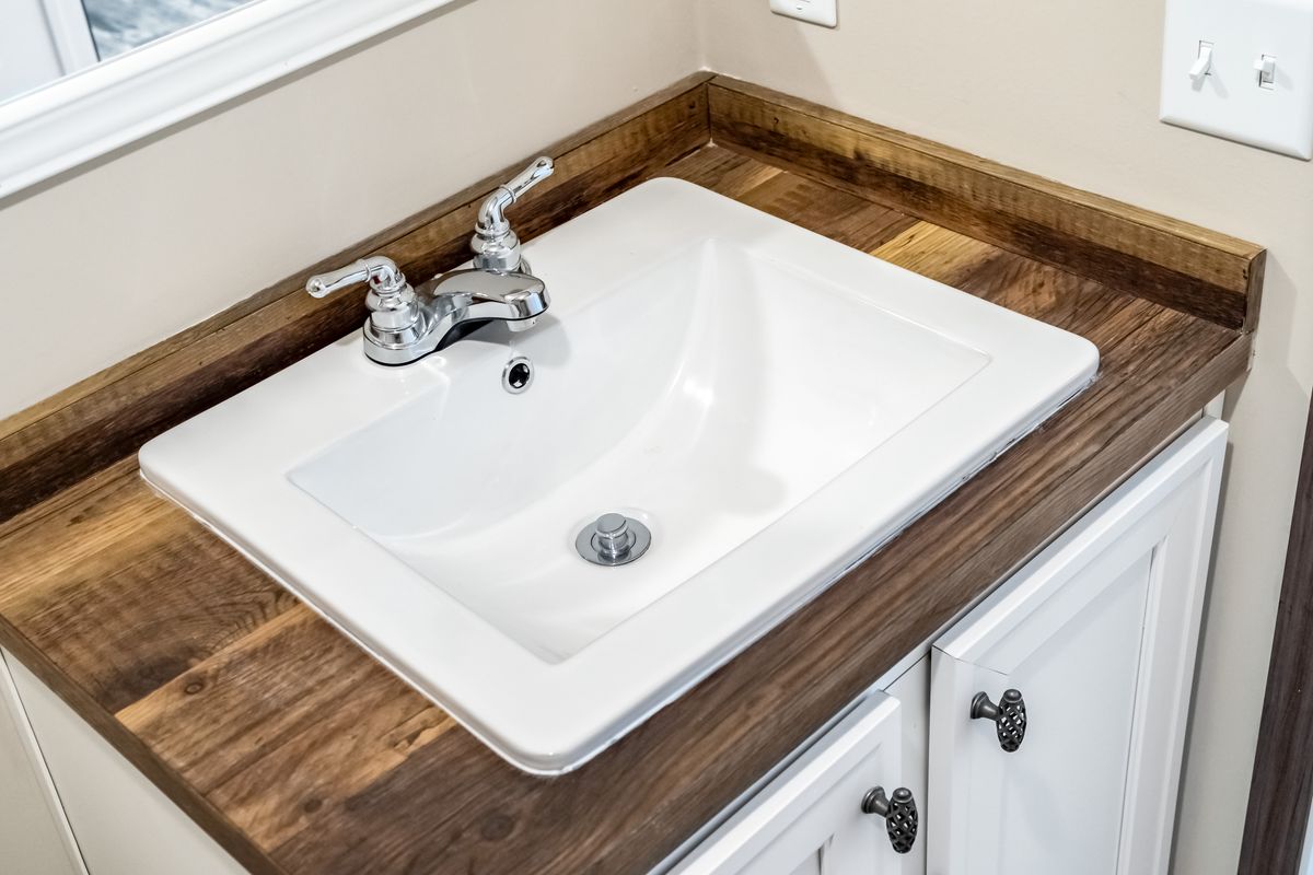 A bathroom sink with a wooden counter top.