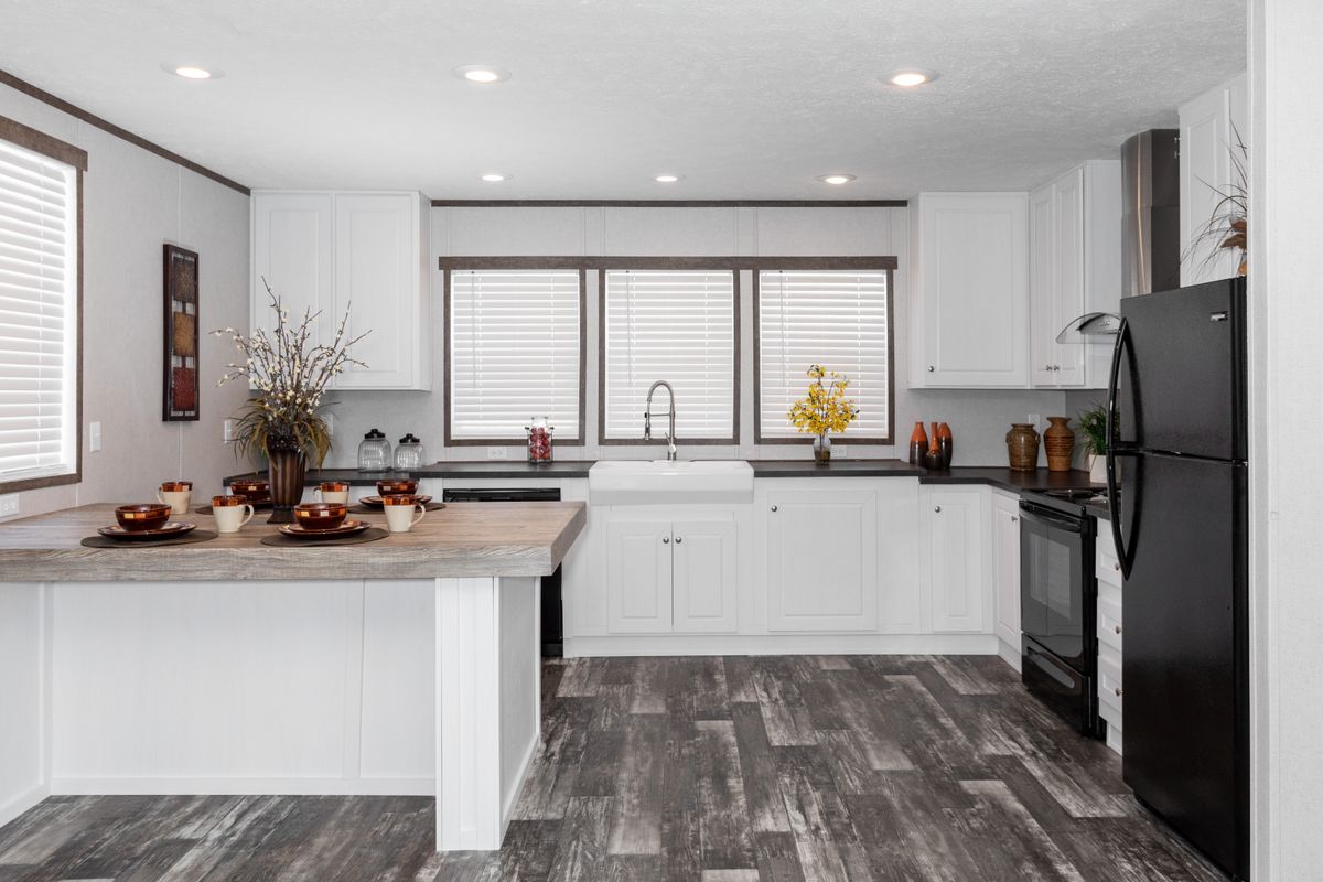 A kitchen with white cabinets and wood floors.
