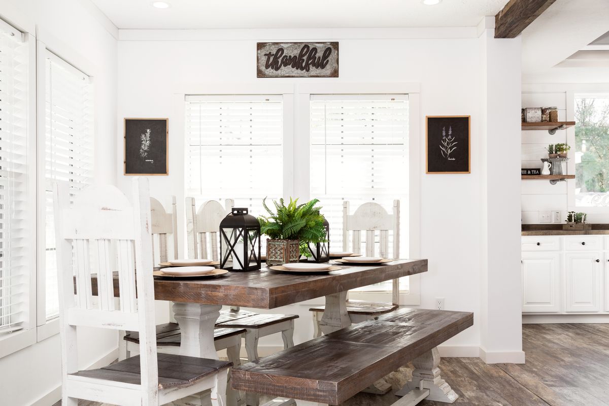A white kitchen with wood floors and a wooden table.
