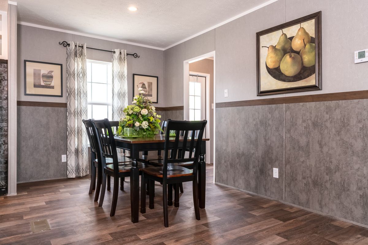 A dining room in a mobile home with hardwood floors.
