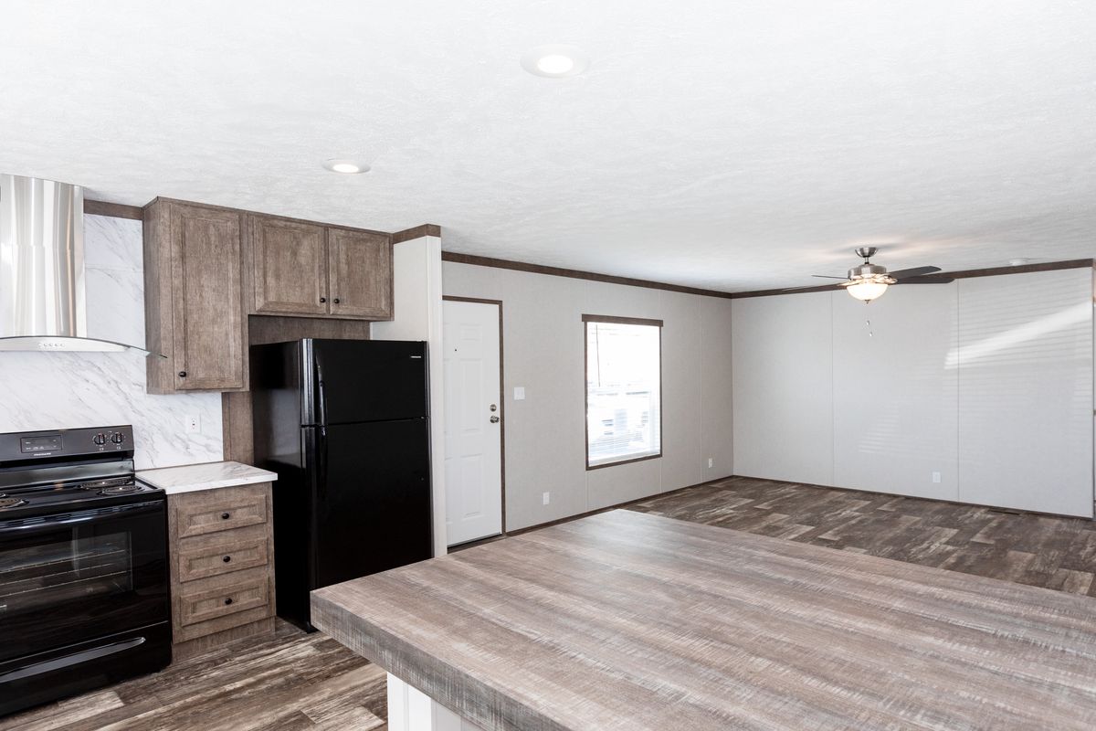 A kitchen in a mobile home with wood floors and a stove.
