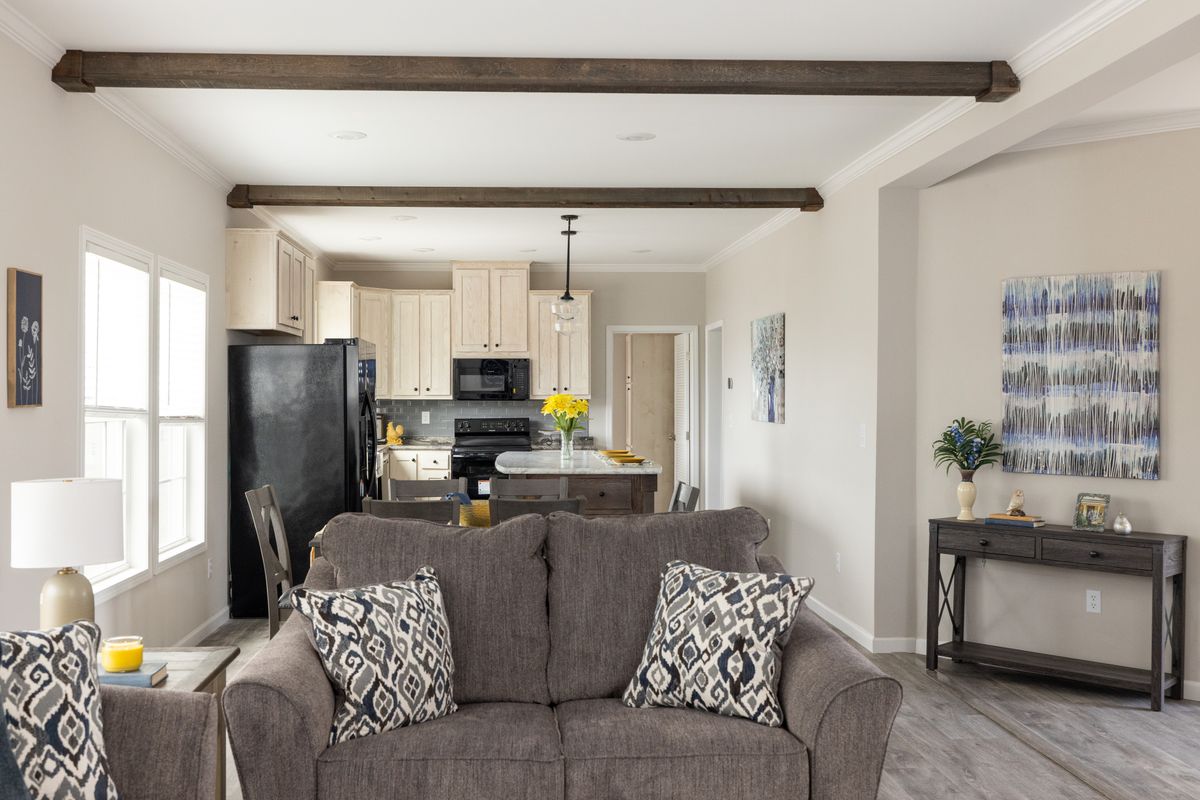 42ebf9dc-46a7-4625-8793-8923590033d0 A living room with a gray couch and wood beams.