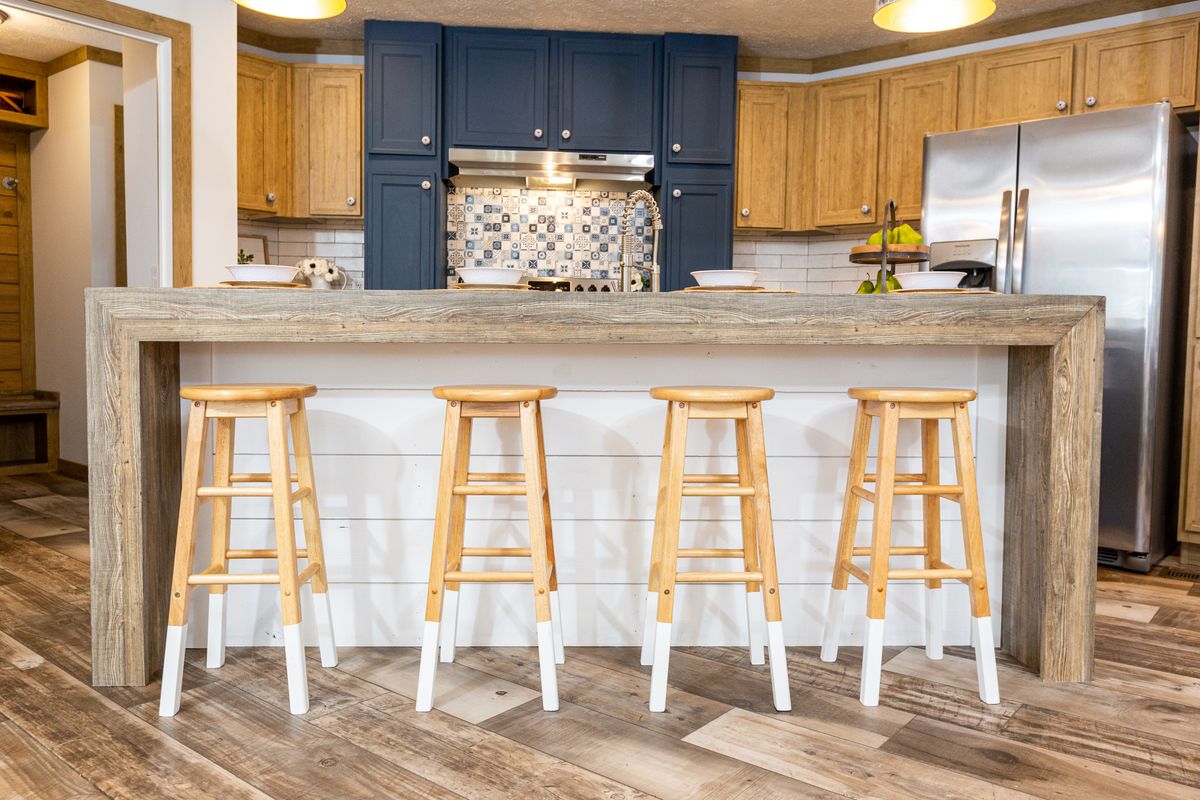A kitchen with bar stools and wood floors.