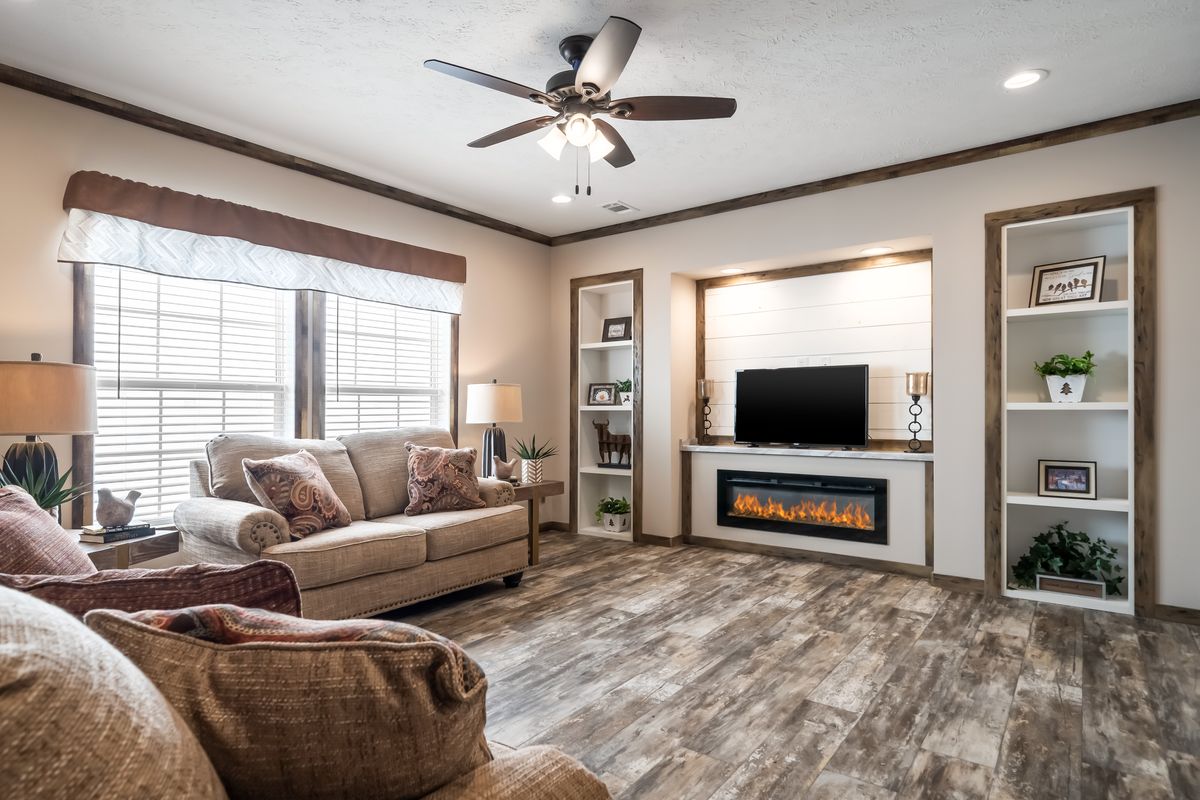 A living room in a mobile home with wood floors and a fireplace.
