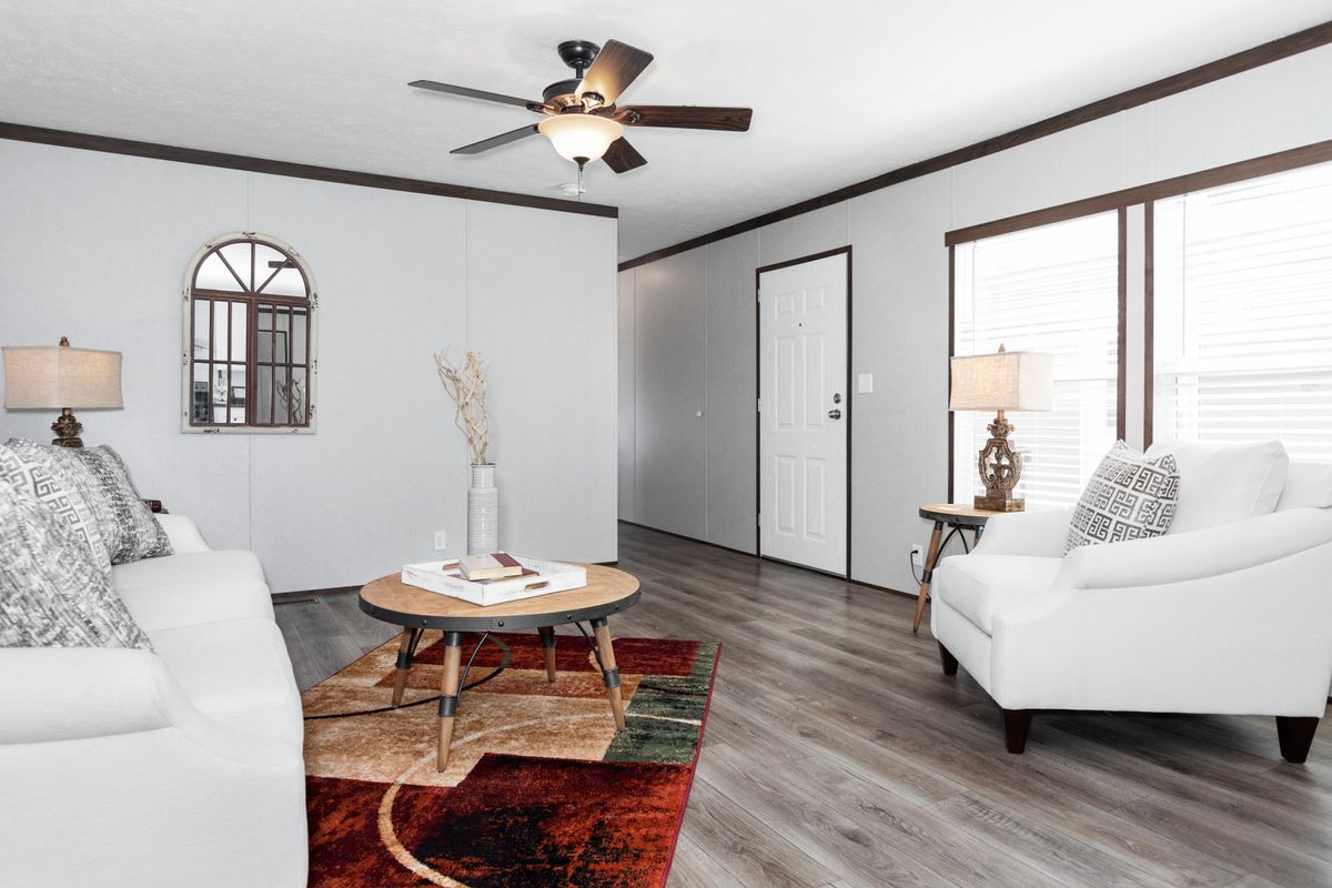 A living room with white furniture and a ceiling fan.