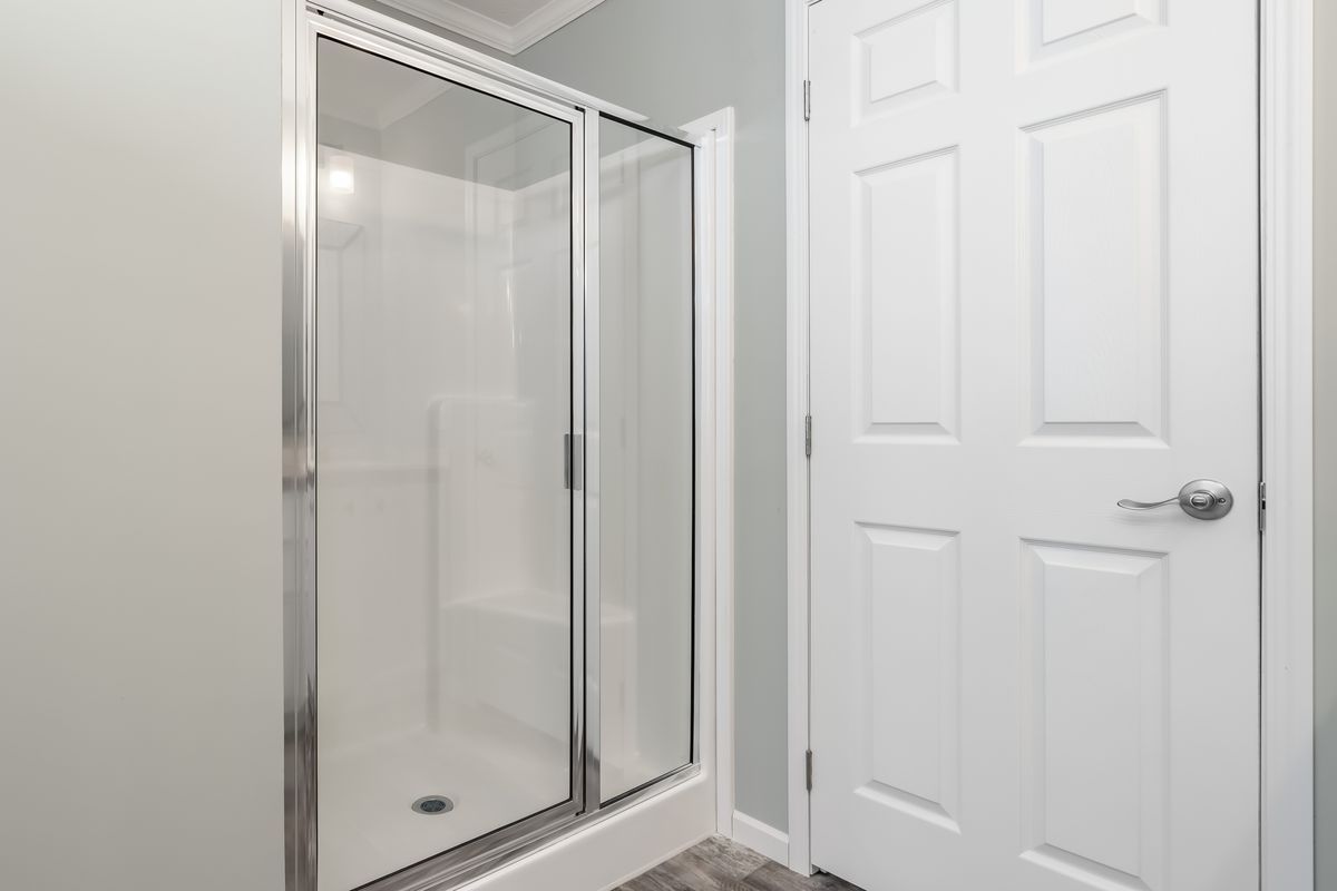 490d2a1f-4929-4e6c-9639-3a85dcaa44c0 A bathroom with a shower stall and a white door.