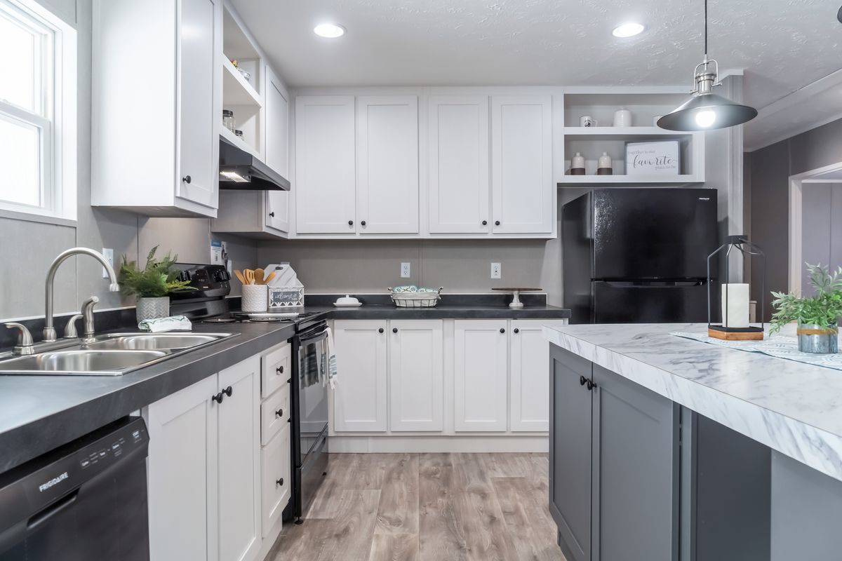 A kitchen with white cabinets and black counter tops.