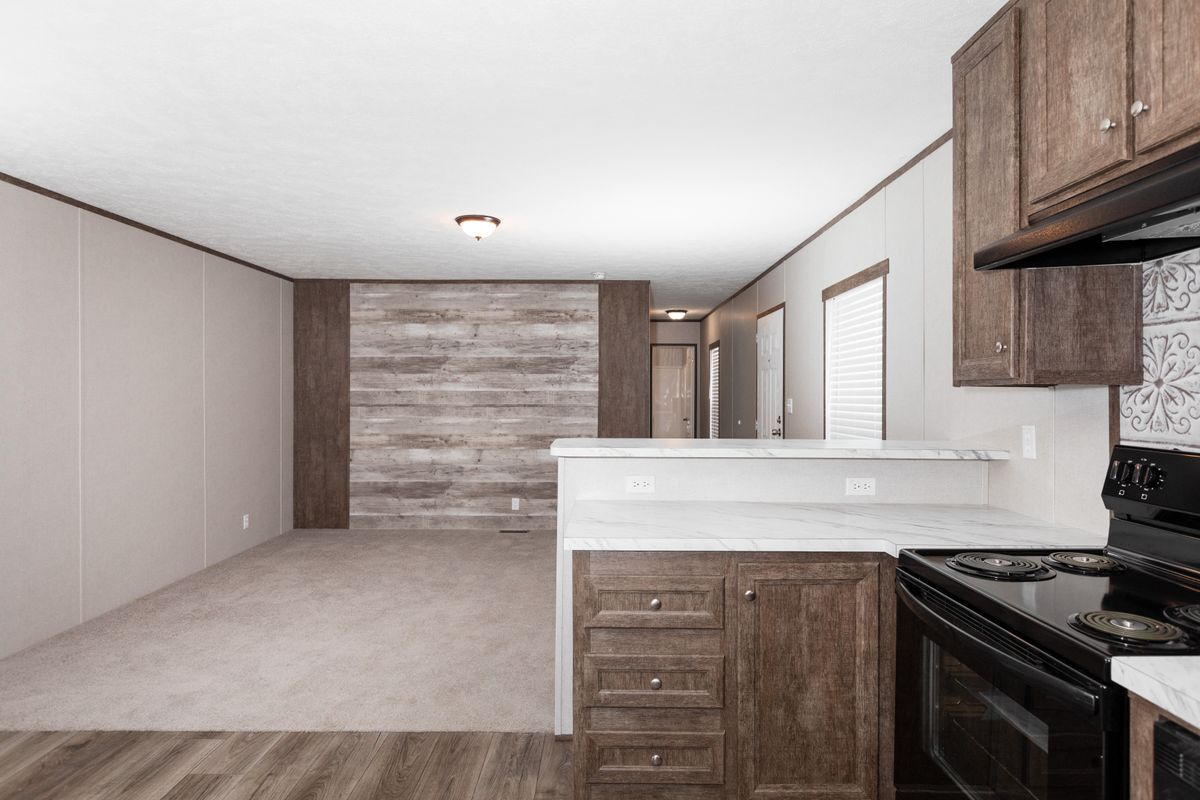 4d3b0b78-9044-48f3-9ce9-3247617763ec A kitchen in a mobile home with wood floors and a stove.