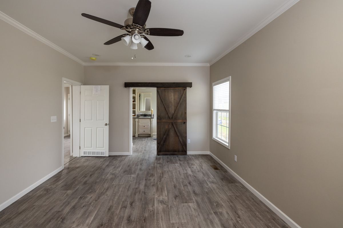 4eb323dd-23d4-42eb-a8d2-1da1d805c88e An empty room with wood floors and a ceiling fan.
