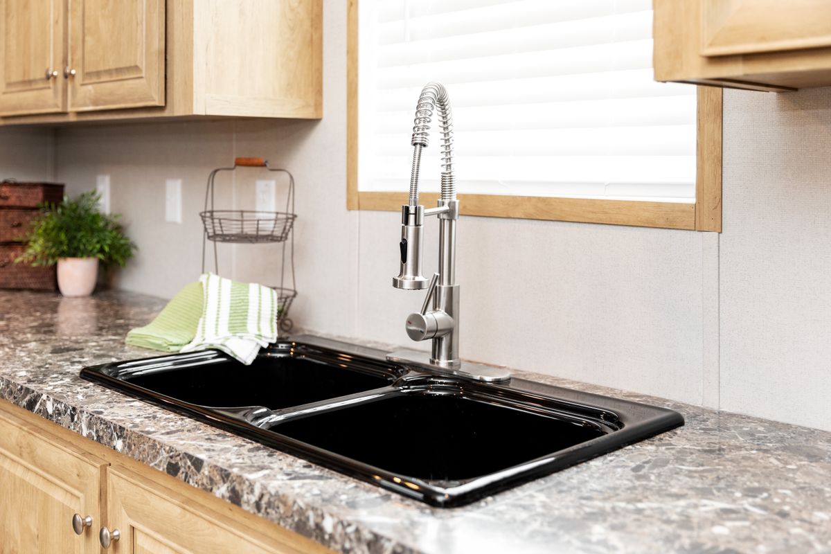 A kitchen with black granite counter tops and stainless steel sink.