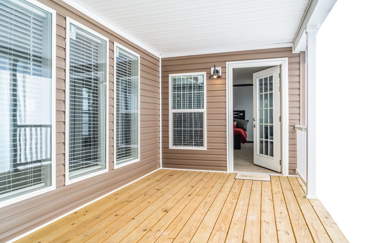 A porch with wooden flooring and sliding glass doors.
