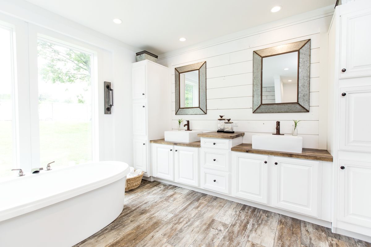 A white bathroom with wood floors and a tub.