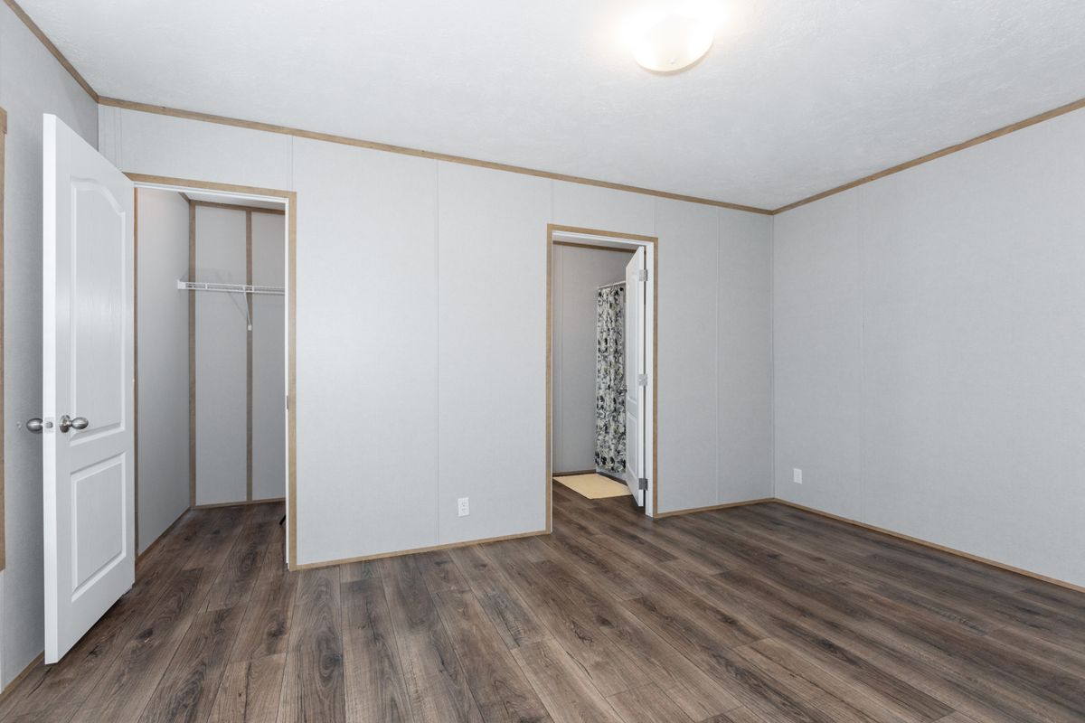 An empty room with wood floors and white walls.