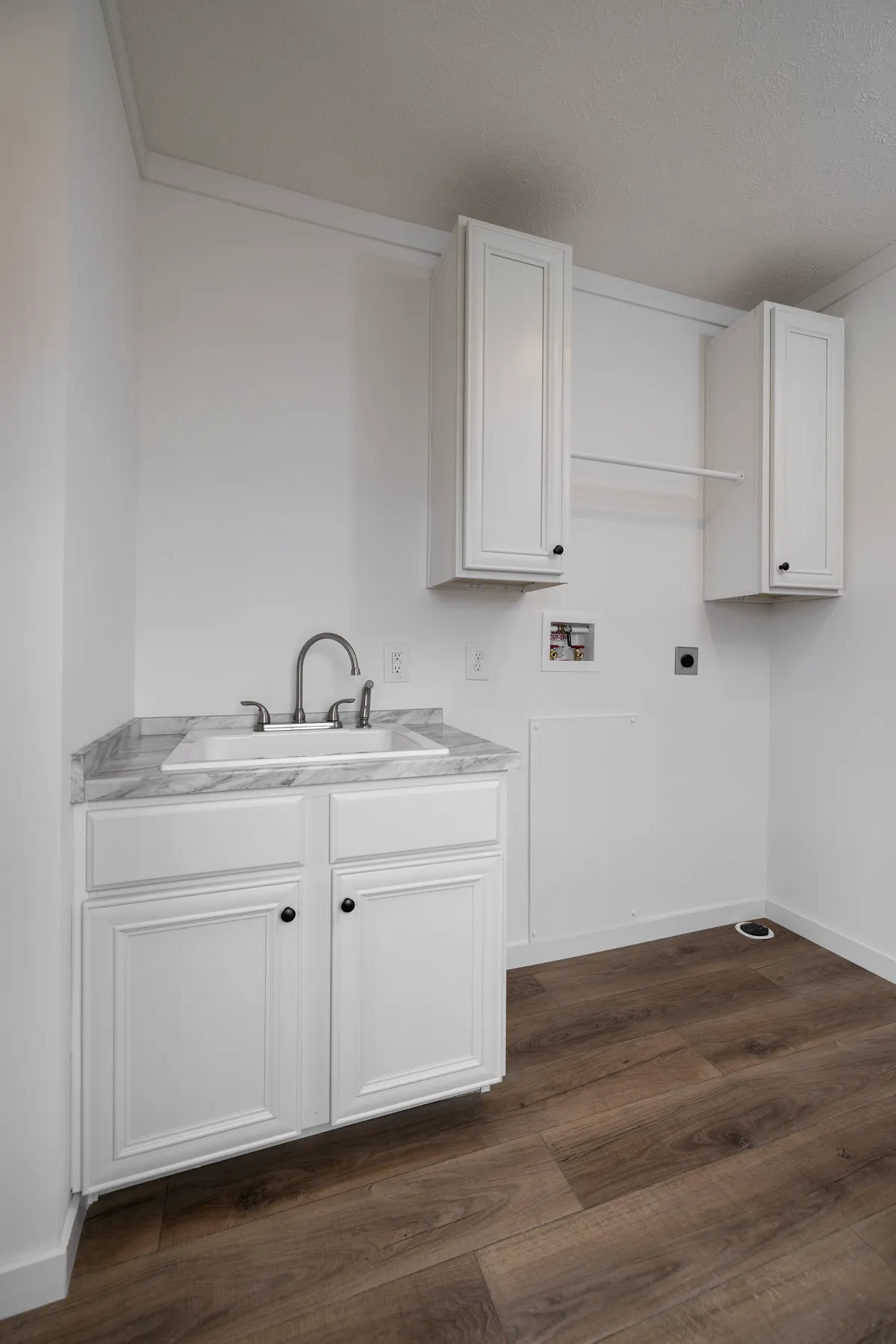 5627b471-e7d3-40fa-8036-156ca8aac5cc An empty kitchen with white cabinets and wood floors.