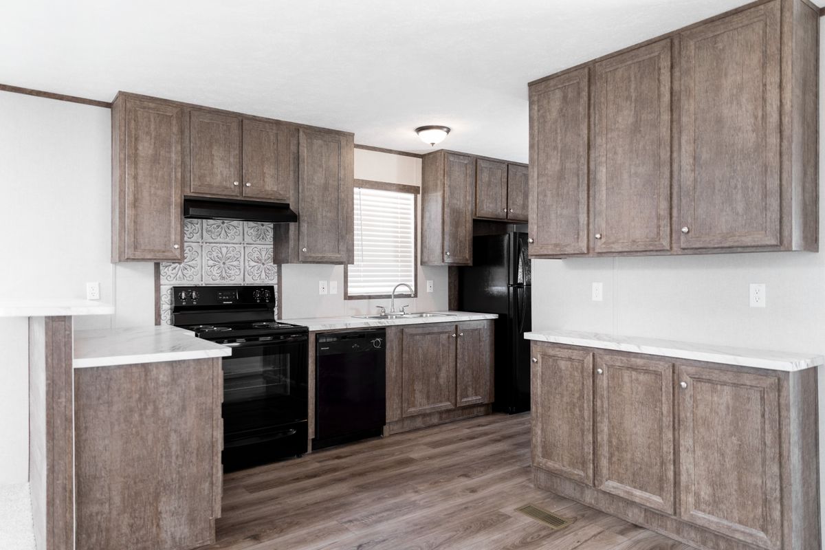 56f7e319-04f6-4198-ac34-12d92b920b95 A kitchen in a mobile home with wood cabinets and black appliances.